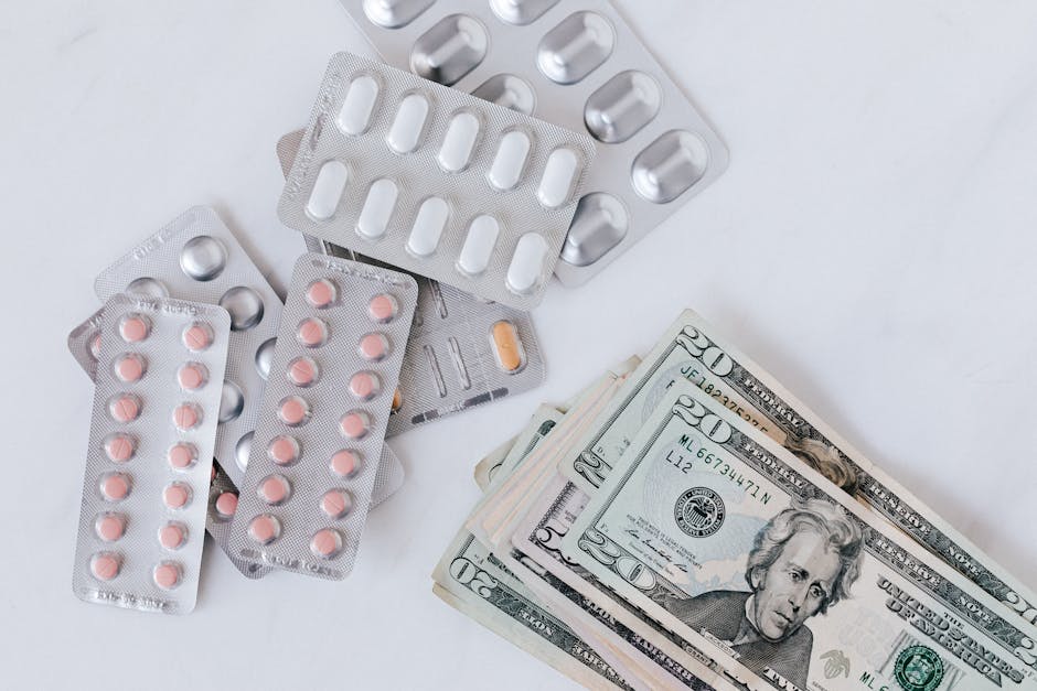 A collection of blister packs containing various pink and orange pills scattered on a white surface, with a stack of US twenty-dollar bills positioned nearby. The pills are in silver and clear blister